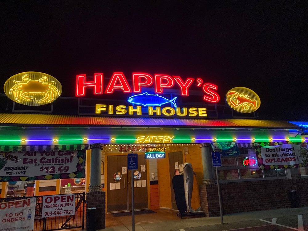 Colorful neon-lit exterior of Happy's Fish House at night.