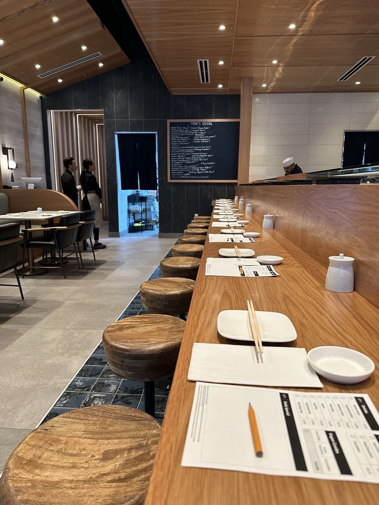Hatsuyuki Handroll Bar with a long wooden sushi counter and neatly set stools.