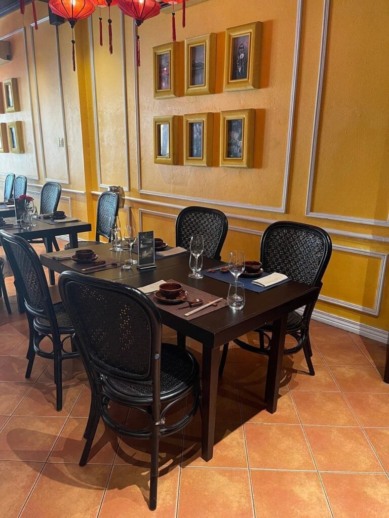 Stylish dining room at Home Hoi An with orange walls, black chairs, and decorative red lanterns.