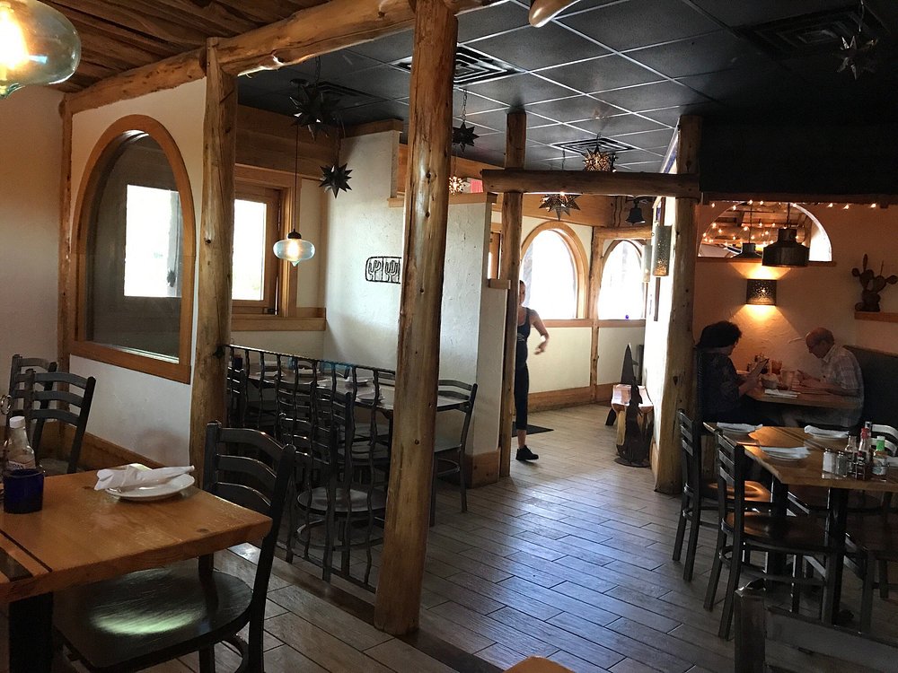 Interior of K38 Baja Grill showing rustic wooden beams, arched windows, and cozy seating.