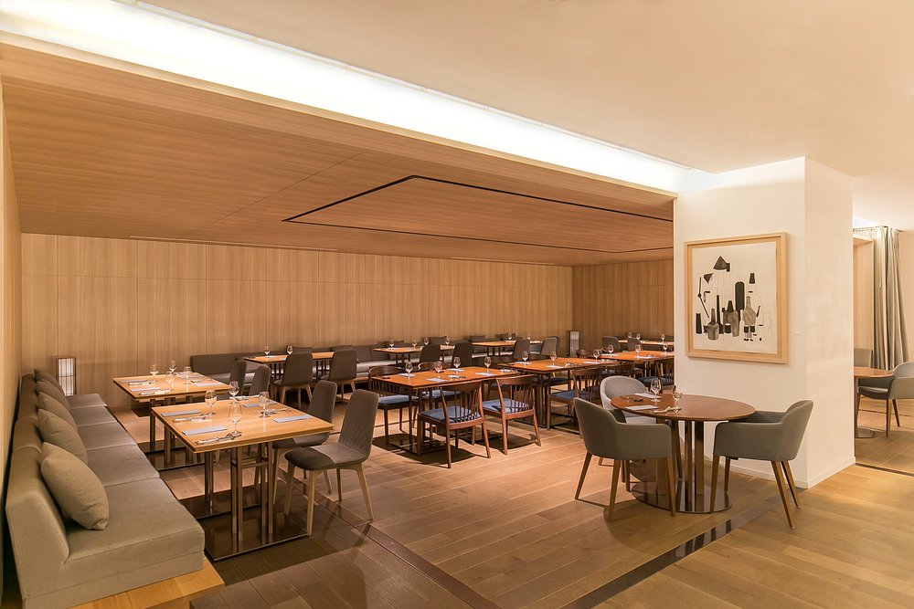 Modern, minimalist dining room at Kitchen Kanra with wooden interiors and neatly set tables.