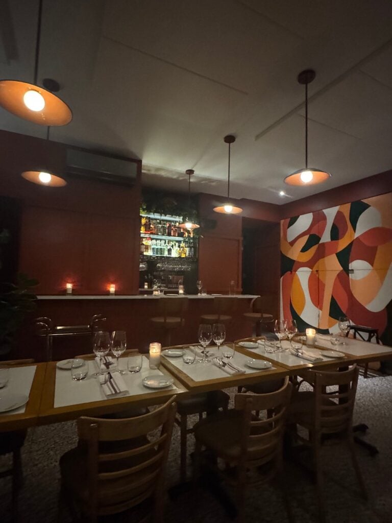 Bright and welcoming dining room at Le Clocher Penché, set with white tablecloths and red seating.