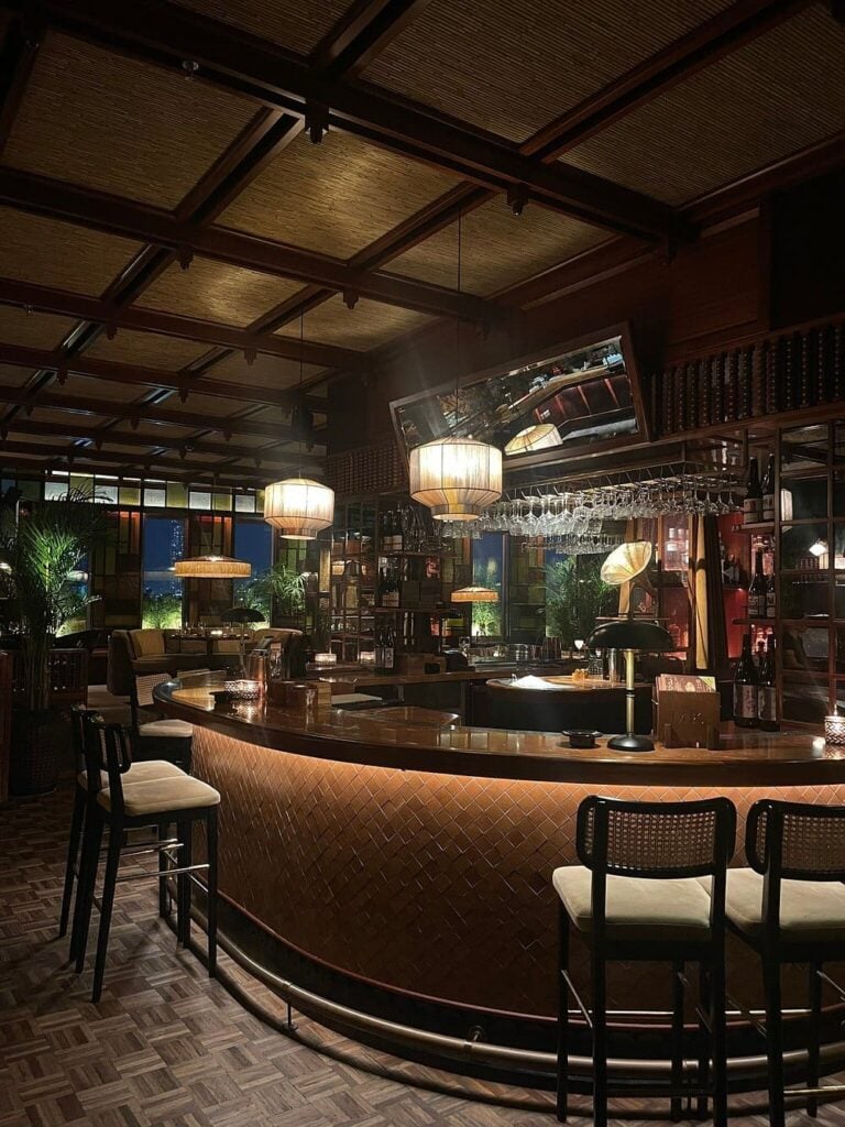 Mimi Kakushi’s dimly lit bar with woven textures, vintage lamps, and warm wood accents.