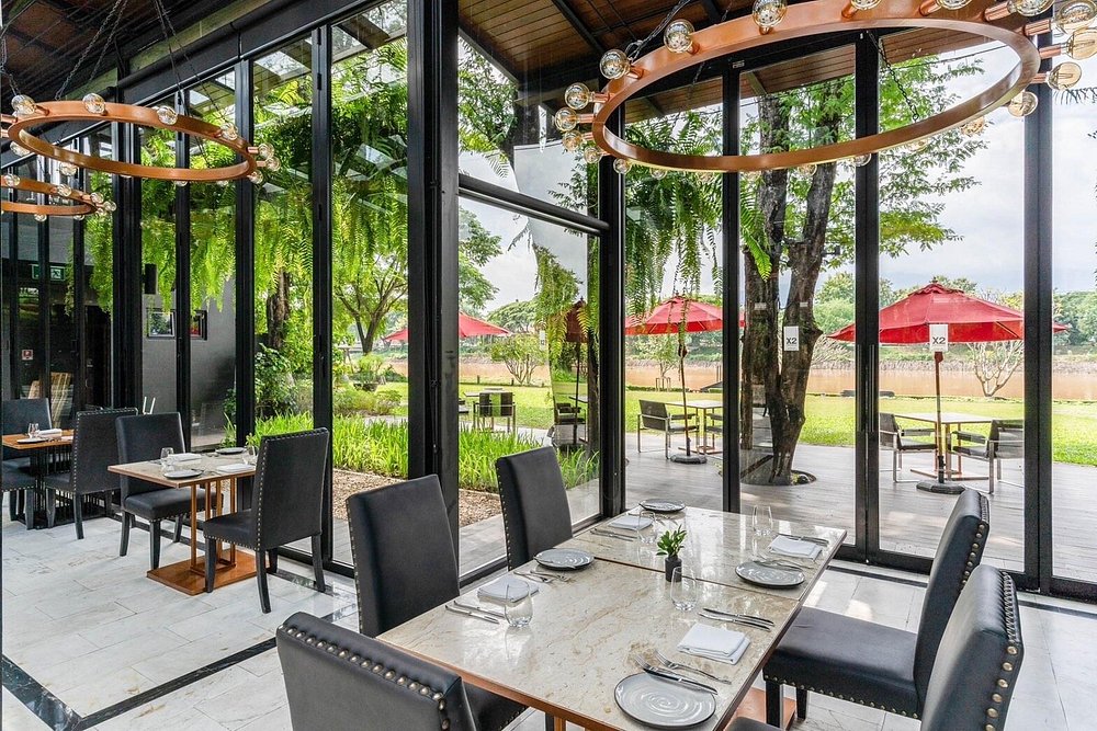 Oxygen Dining Room with elegant tables, large windows, and garden views with red umbrellas.