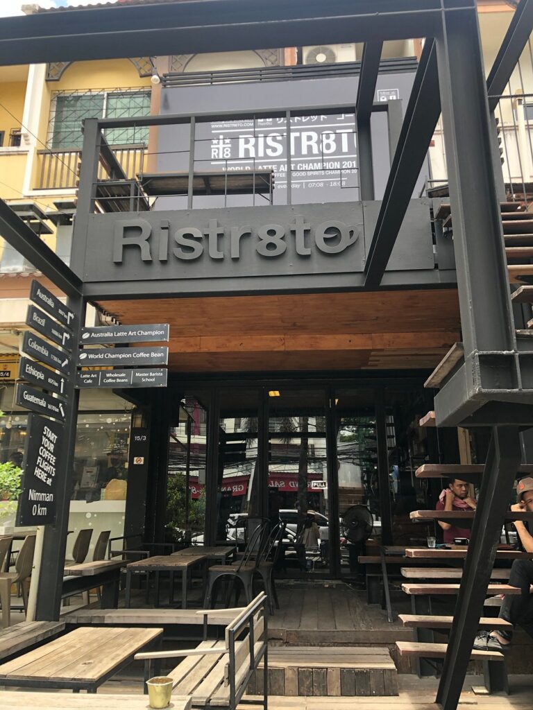 Ristr8to café with a modern black exterior, wooden seating, and street view.