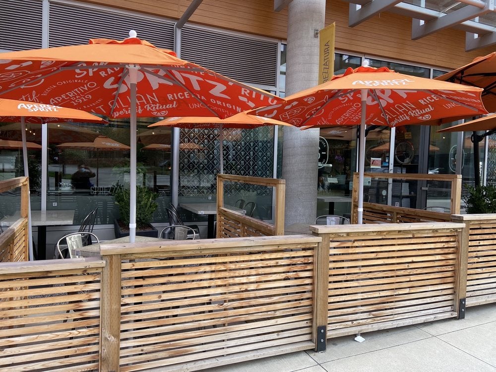 Outdoor patio seating with orange Aperol Spritz umbrellas at Sprezzatura.