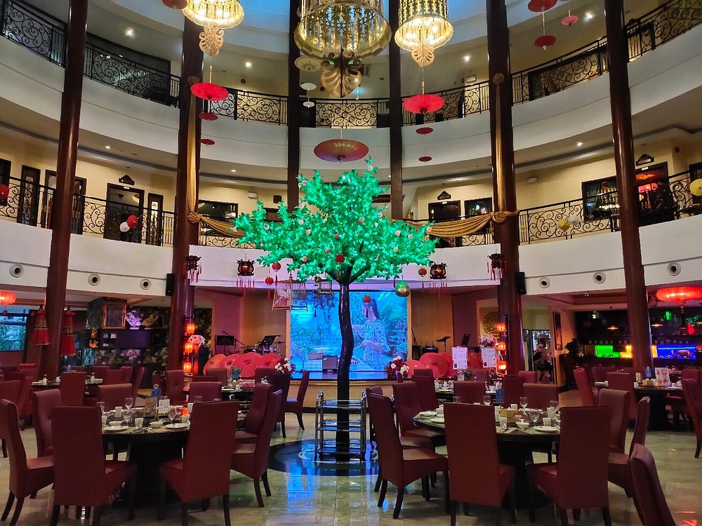 TULOU restaurant with elegant red seating, a glowing tree centerpiece, and a grand circular layout.