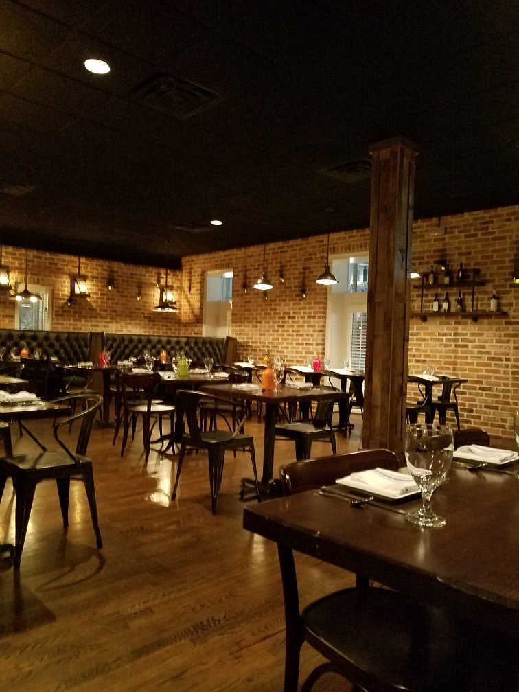 Cozy dining room at Tarantelli's featuring dark wood tables, black chairs, and warm lighting.