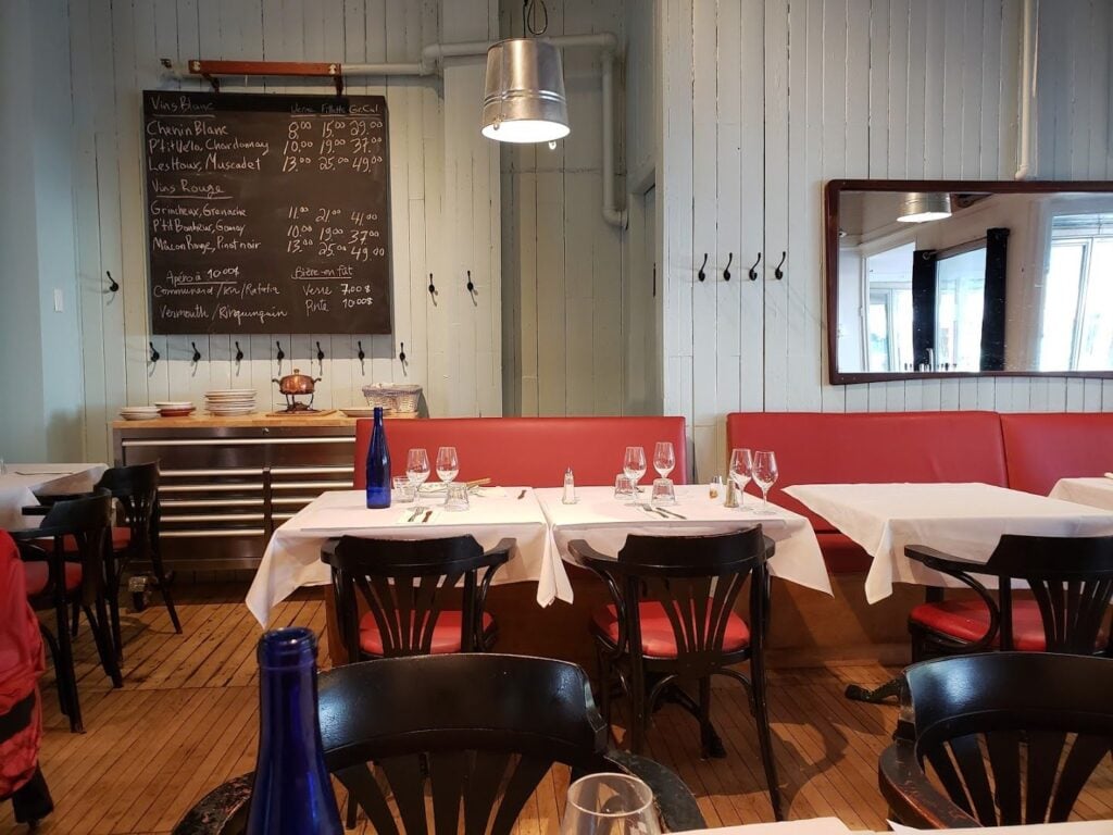 Dining area of Thania et Louis du Pied Bleu, a casual French bistro with red banquettes and a chalkboard wine list.