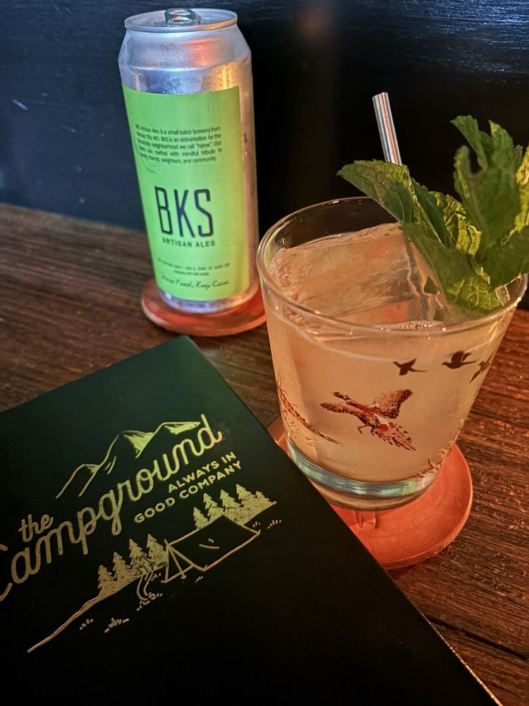 Craft cocktail and local beer on a wooden table at The Campground.