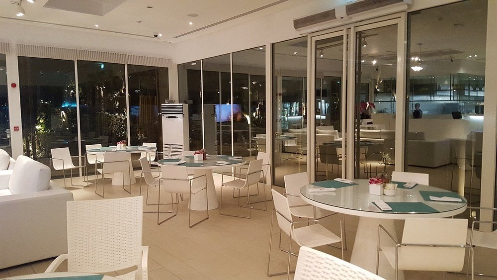 The Farm restaurant interior with white furniture, glass walls, and serene minimalist decor.