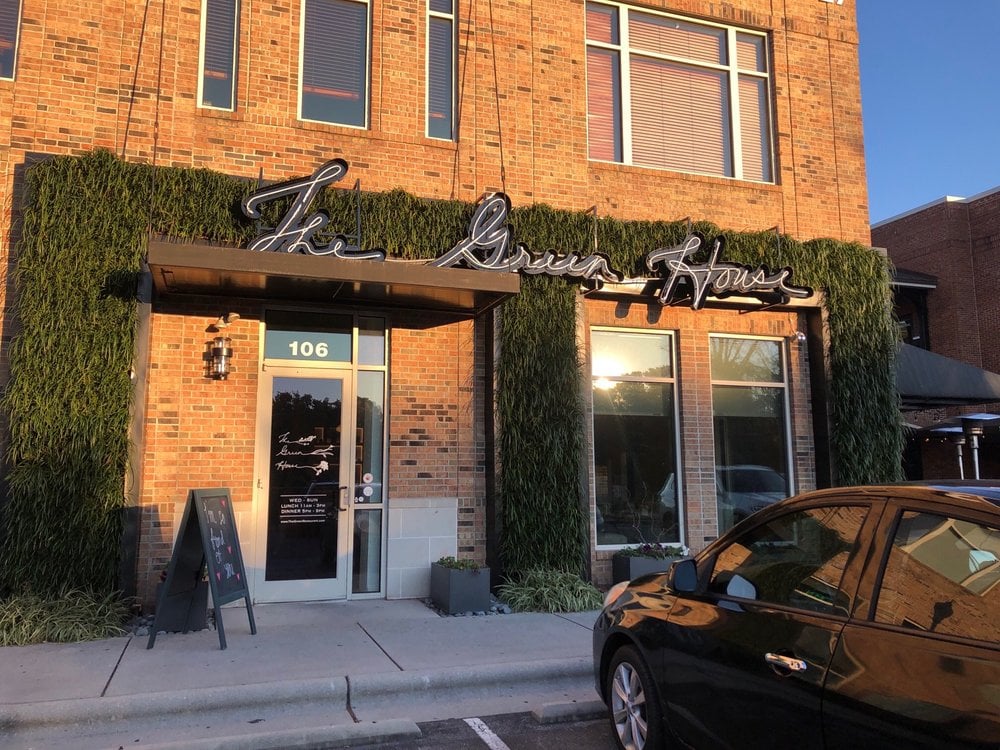 Exterior of The Green House Restaurant with a brick facade and greenery framing the entrance.