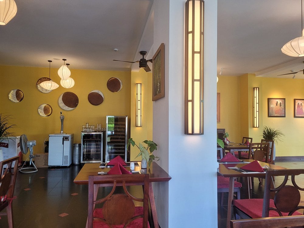 Bright and modern interior of The Soul Restaurant with yellow walls, hanging lights, and red-accented tables.