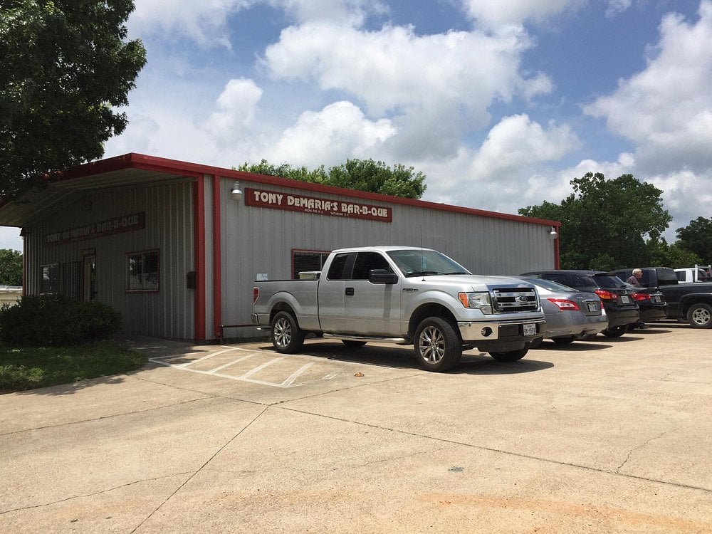 Exterior of Tony DeMaria's Bar-B-Que with parked pickup trucks.