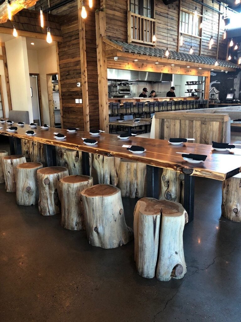 Wabi House interior with rustic wood decor, log stools, and an open kitchen.