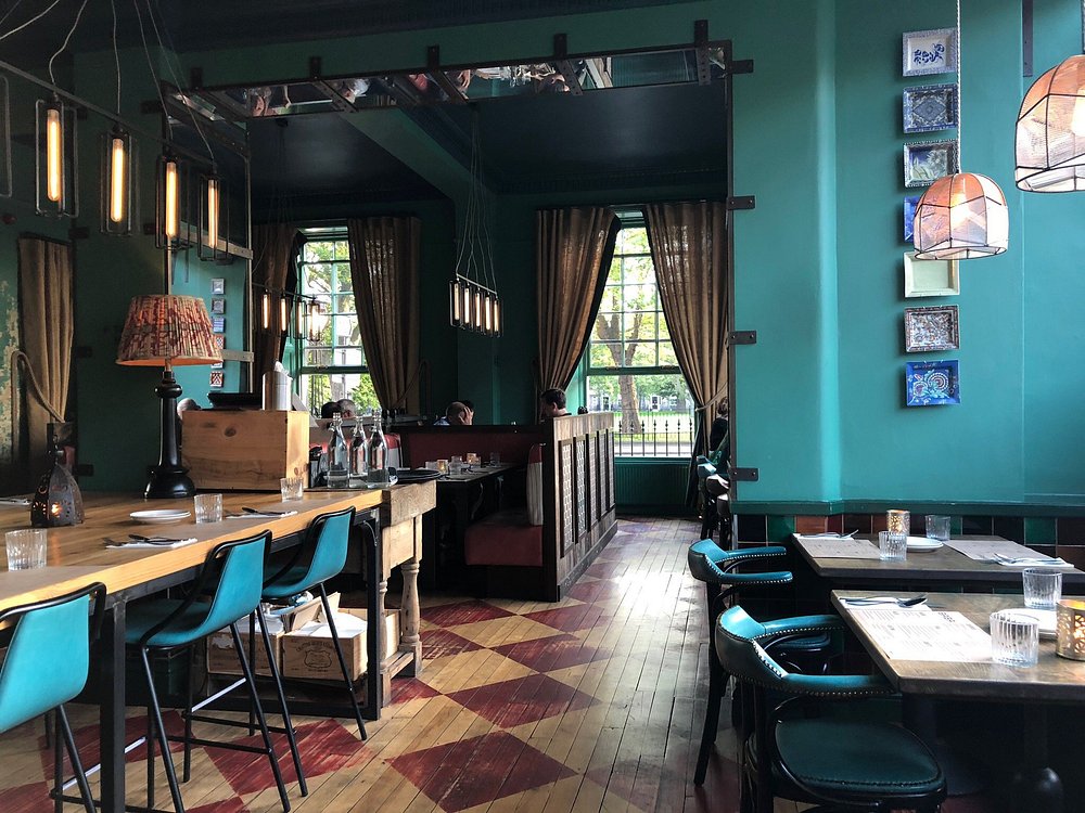 Vibrant and eclectic interior at Baba Midlothian with teal walls and patterned floors.