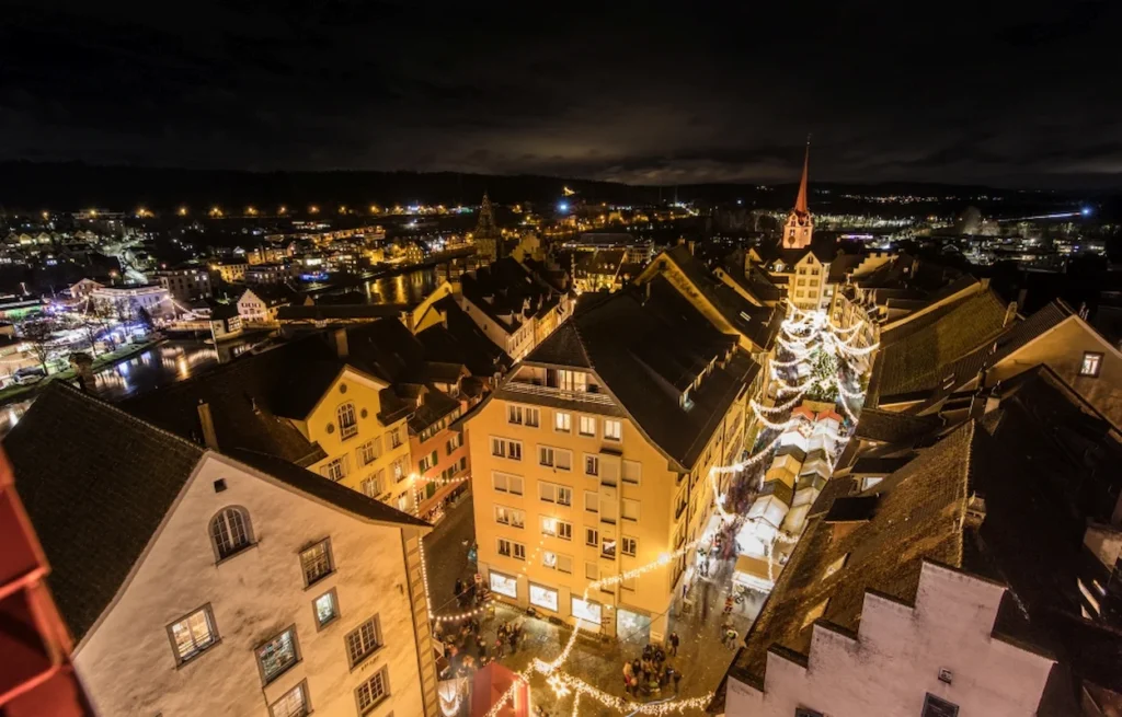 Night aerial view of glowing streets and historic rooftops at the Bremgarten Christmas Market