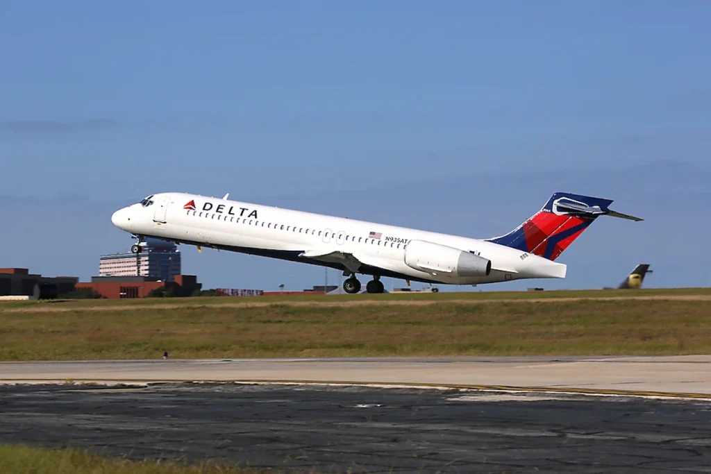 Delta Air Lines Boeing 717 twin-engine passenger plane taking off from an airport runway against a blue sky