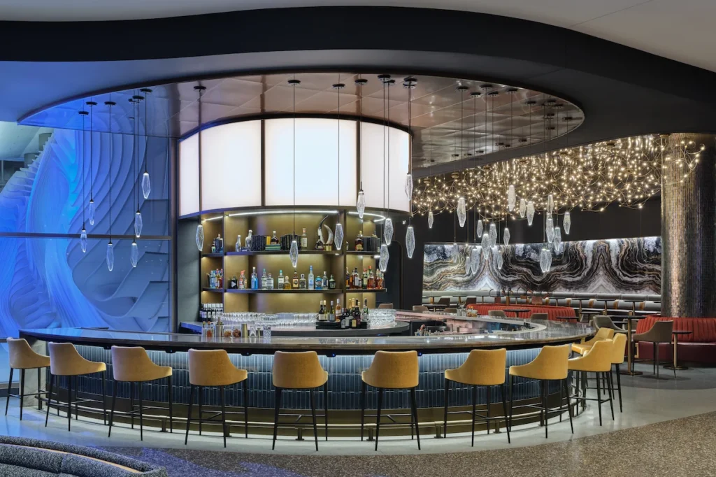 Modern circular bar with yellow stools and elegant lighting inside a Delta Sky Club airport lounge