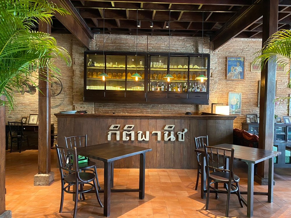 Kiti Panit interior with rustic brick walls, wooden furniture, and a vintage-style bar.