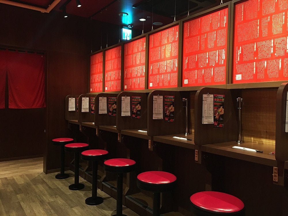 Individual ramen booths with red stools at Ichiran, a famous Japanese ramen restaurant.