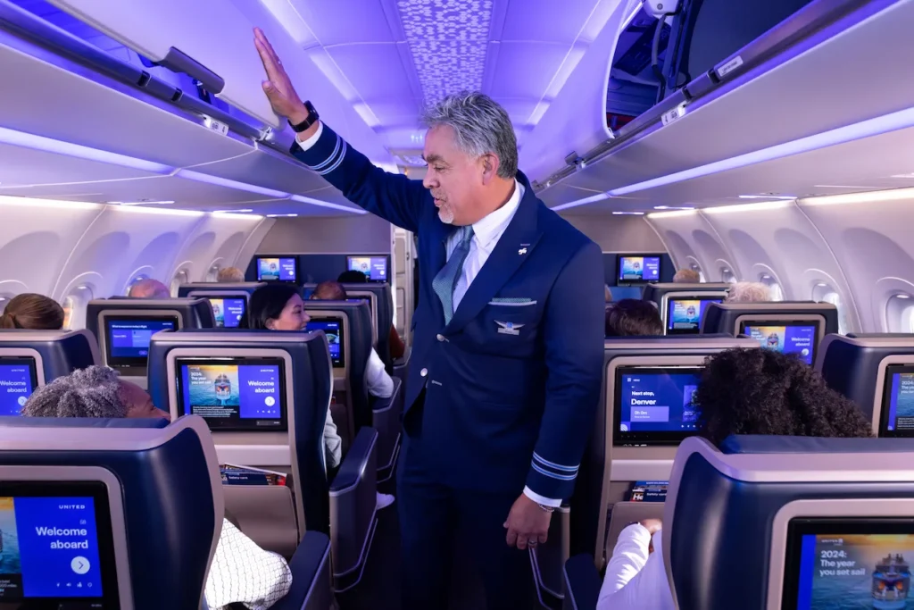Flight attendant greeting passengers inside airplane cabin