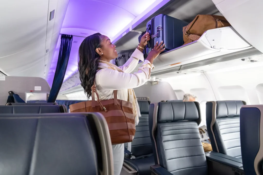United Airlines passenger placing luggage in overhead bin