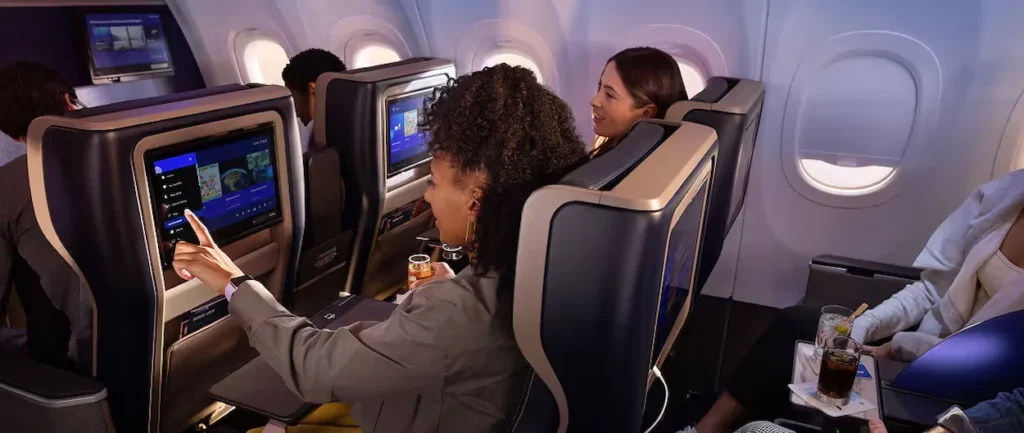 Passengers using inflight entertainment screens in United Airlines premium seats.