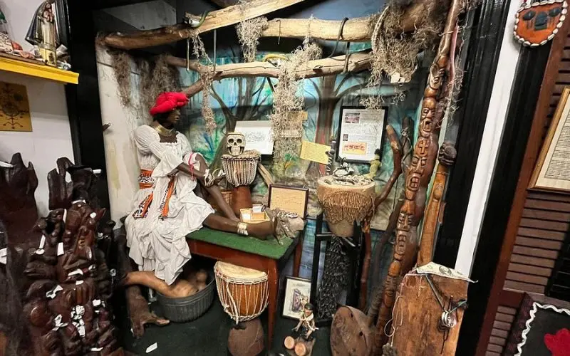 Voodoo Museum with drums, artifacts, and a mannequin dressed in traditional clothing.