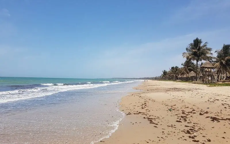 Serekunda Beach in Gambia with sandy shore and palm huts.