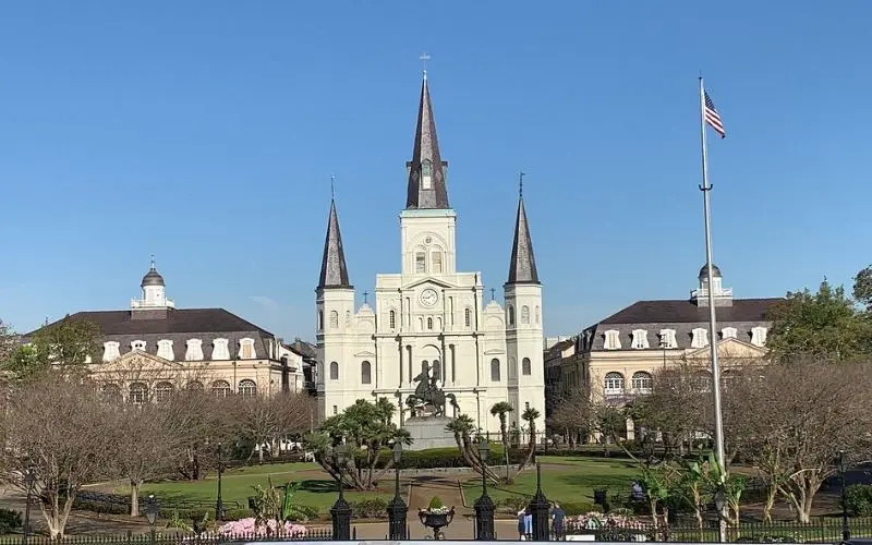 St. Louis Cathedral with its white facade and tall spires overlooking a garden square.