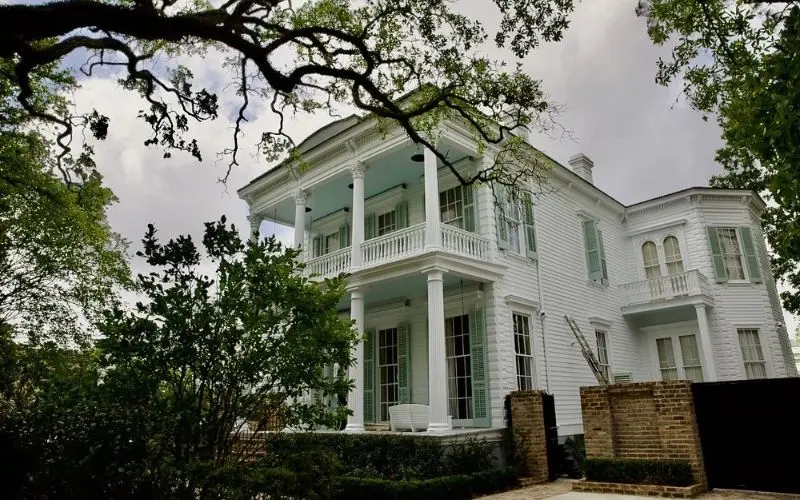 Garden District with a grand white house surrounded by trees and greenery.
