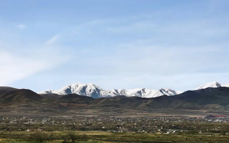 A valley town with snow-capped mountains rising dramatically in the distance.