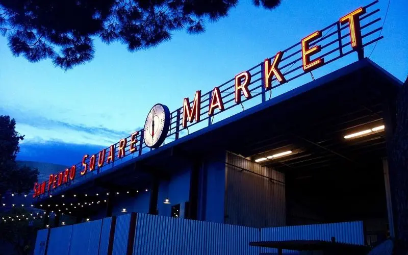 The San Pedro Square Market sign glows at dusk.