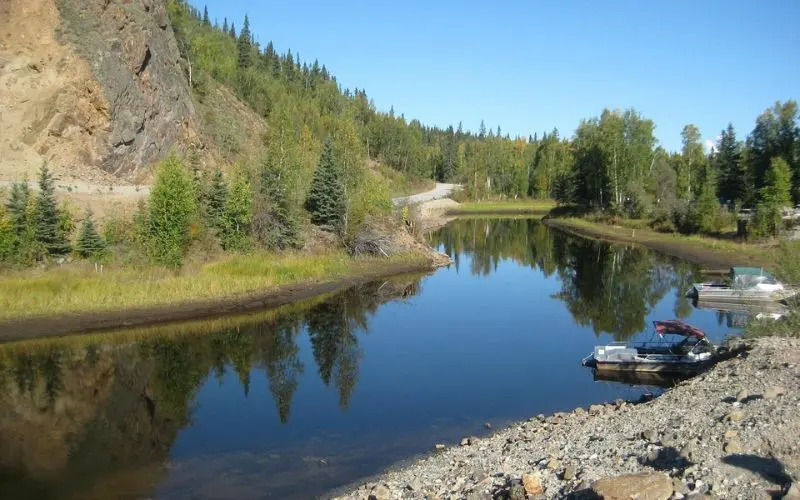 Calm river with boats and forested hills in Fairbanks.