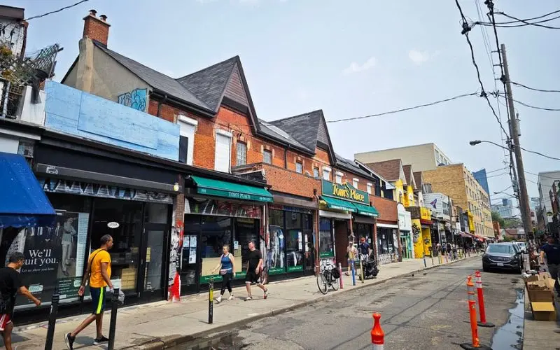Colorful storefronts and people walking along the street at Kensington Market in Toronto.