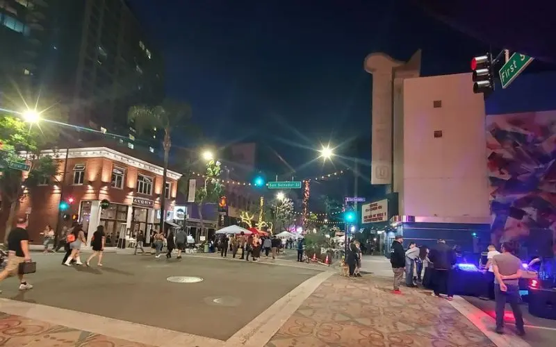 People gather on a lively street corner in the SoFA District at night.