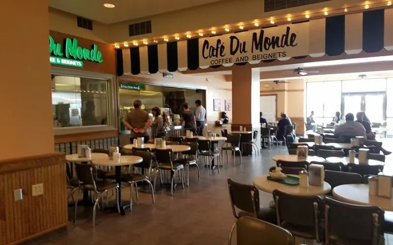 Café du Monde with tables and people ordering coffee and beignets.