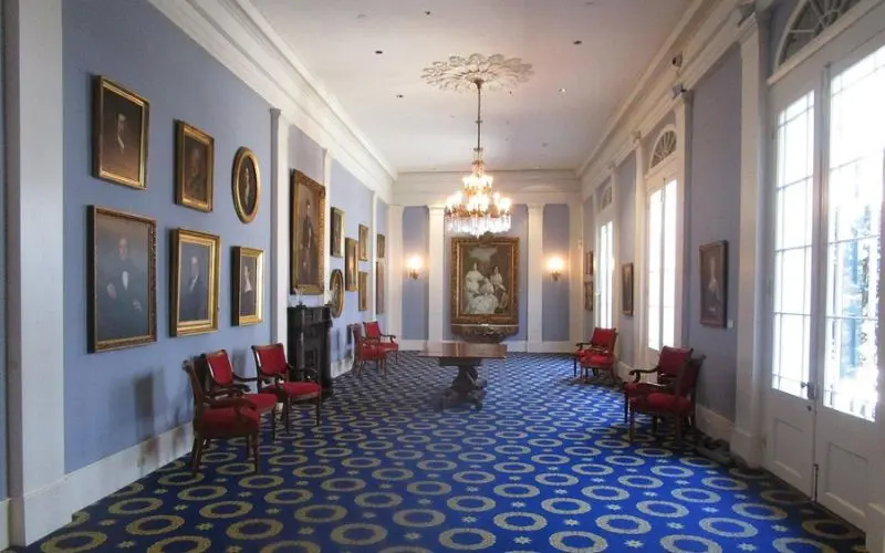 Historic New Orleans Collection with portraits on blue walls and a chandelier above.
