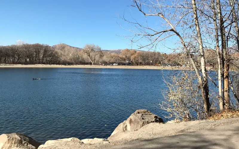 Orem Utah lakeside view with calm water and bare trees.