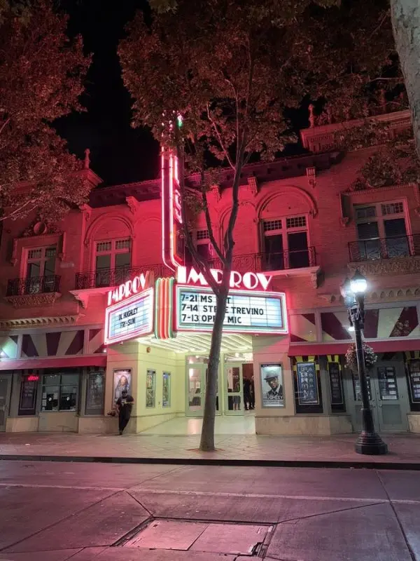 The neon-lit San Jose Improv comedy club at night.