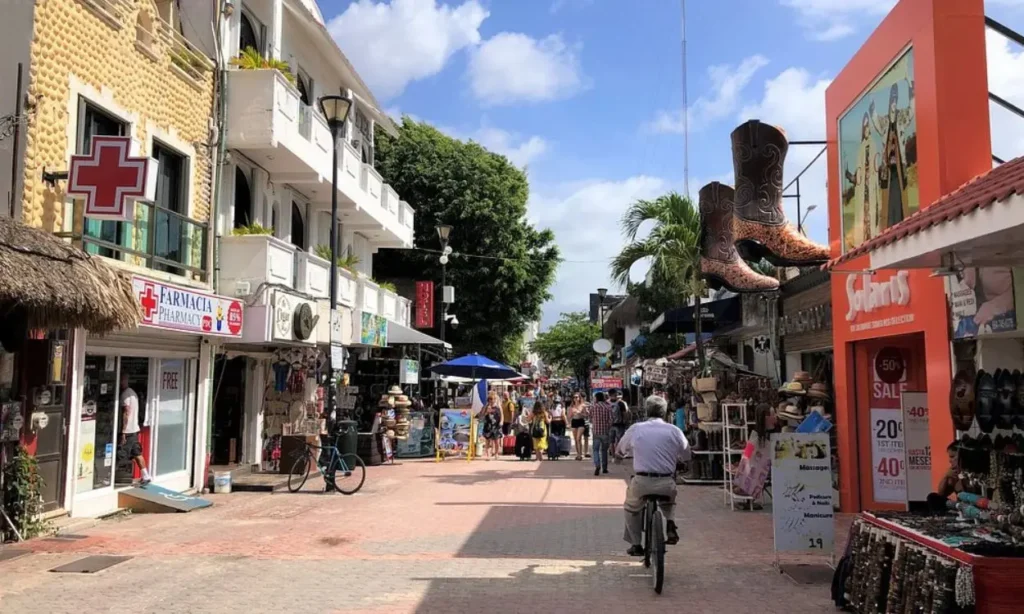 Bustling pedestrian street with shops and signs in Playa del Carmen.