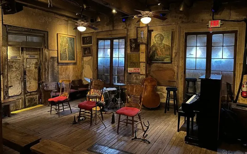 Preservation Hall with wooden floors, vintage paintings, and instruments set up for a jazz performance.