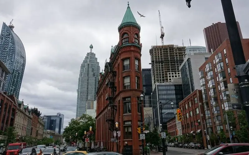 Historic red-brick Gooderham Building among skyscrapers on Queen Street West in Toronto.