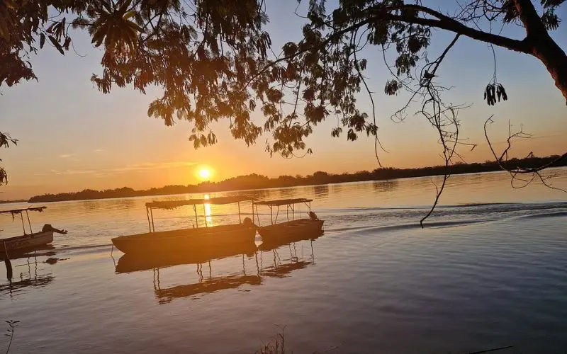 Gambia River with boats at sunset.