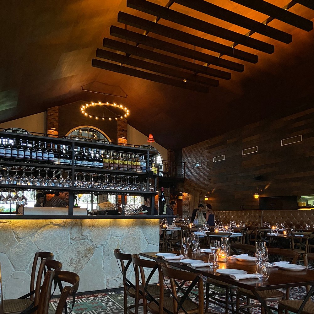 Upscale and moody interior of Barbacoa with wooden beams, ambient lighting, and wine displays.