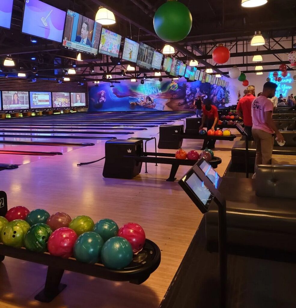 Bowling lanes with colorful balls and large screens at Beach Bowl.