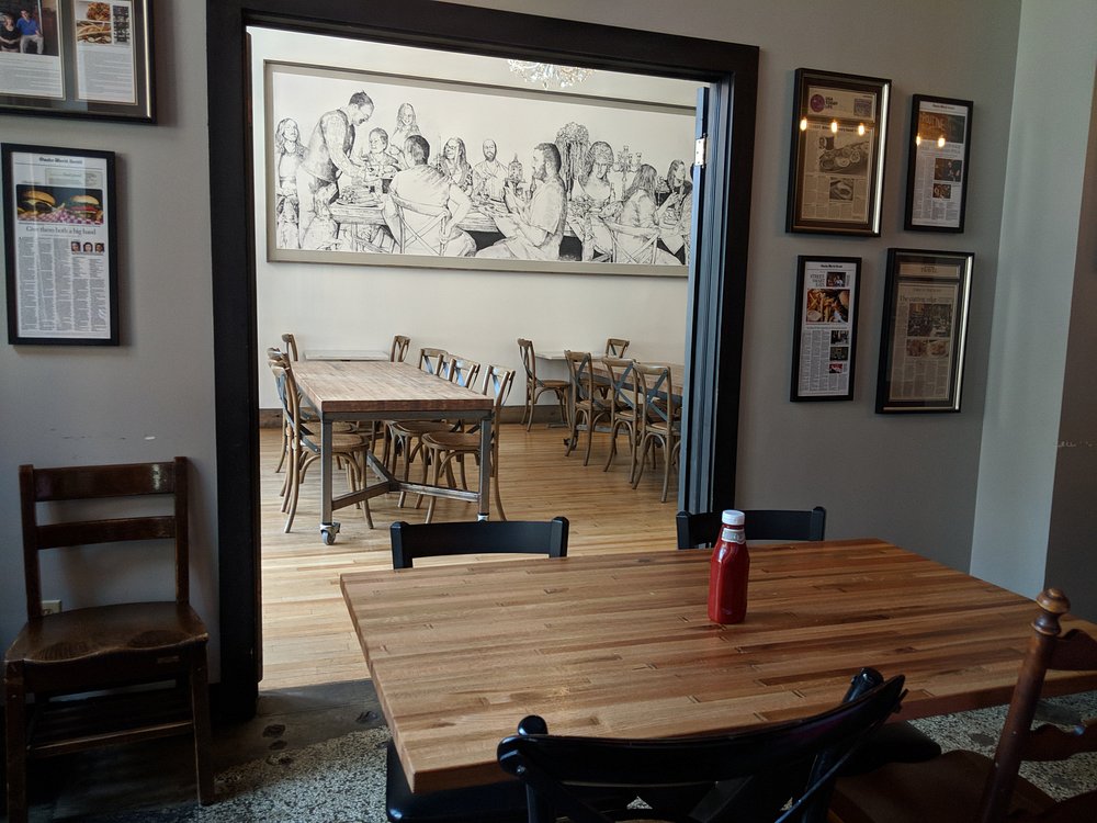 Casual dining space with framed articles and communal wooden tables at Block 16.