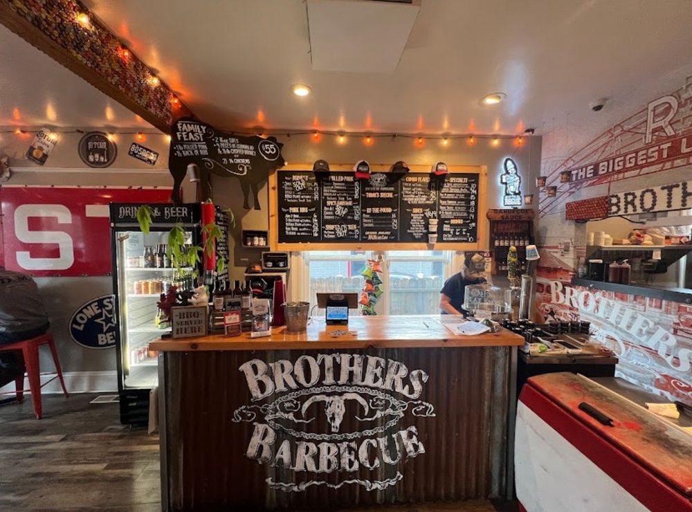 Interior counter of Brothers Barbecue with a rustic theme and chalkboard menu overhead.