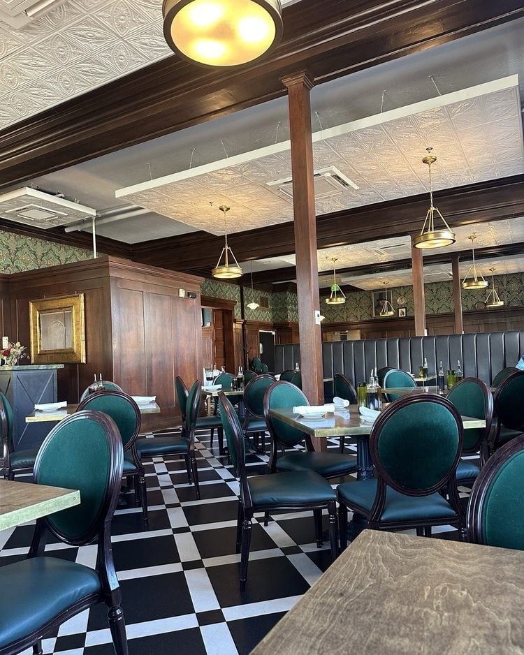 Elegant dining room with green velvet chairs and checkered floors at Caffé Molise.